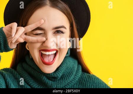 Felice giovane donna che mostra la vittoria gesto sul colore di sfondo Foto Stock