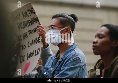 Gruppo di giovani in una protesta silenziosa in città. Uomo che indossa una maschera facciale di protezione che partecipa ad un colpo. Foto Stock