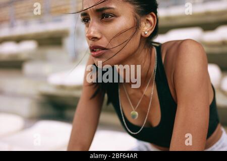 Primo piano di un atleta femminile che si stanca dopo una sessione di allenamento allo stadio sportivo. Donna in forma dopo corsa su pista stadio. Foto Stock