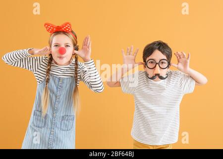 Bambini piccoli nella divertente travestimento sul colore di sfondo. Il giorno degli sciocchi di aprile celebrazione Foto Stock