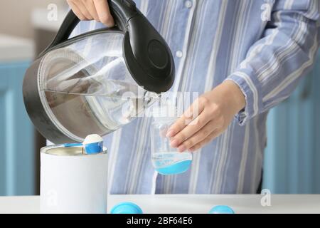 Donna che prepara latte per bambini in cucina Foto Stock