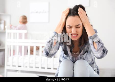 Giovane donna che soffre di depressione postnatale a casa Foto Stock