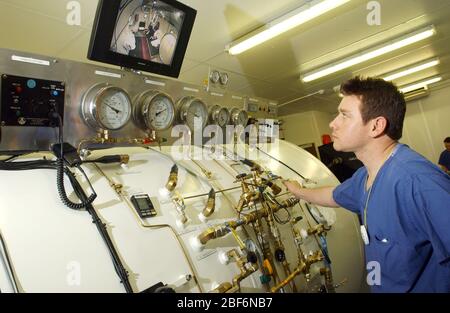 Un tecnico iperbarico monitora il paziente e regola le pressioni nella camera di decompressione. Foto Stock