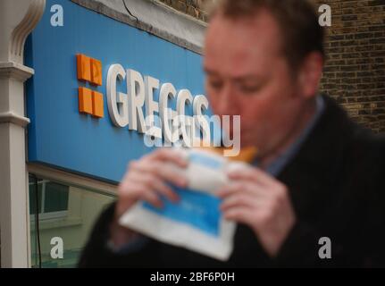 L'immagine mostra: un lavoratore della città di mangiare a Greggs pasty. Foto Stock