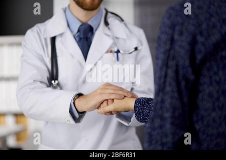 Gentile medico della barba rossa rassicurante la paziente femminile, primo piano. Etica medica e concetto di fiducia, tema della medicina Foto Stock