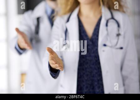 Due medici in piedi e offrendo mano d'aiuto per scuotere la mano o salvare la vita. Aiuto medico, contrastare l'infezione virale e concetto di medicina Foto Stock