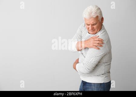 Uomo anziano affetto da sindrome di Parkinson su sfondo grigio Foto Stock