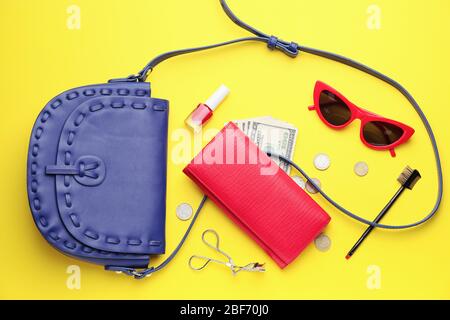 Borsa con portafoglio, denaro e accessori su sfondo colorato Foto Stock