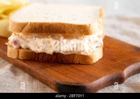 Sandwich di Pimento, gustoso e fatto in casa, con patatine su un rustico asse in legno, vista laterale. Primo piano. Foto Stock