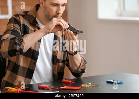 Tecnico elettronico che ripara il telefono cellulare nel centro di assistenza Foto Stock