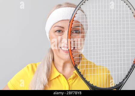 Giocatore di tennis femminile maturo su sfondo chiaro Foto Stock