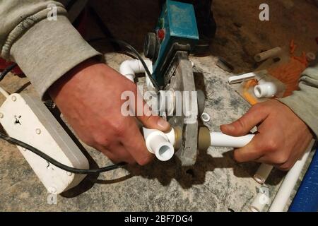 L'operatore saldava due tubi per riscaldare il pavimento con un saldatore.2020 Foto Stock