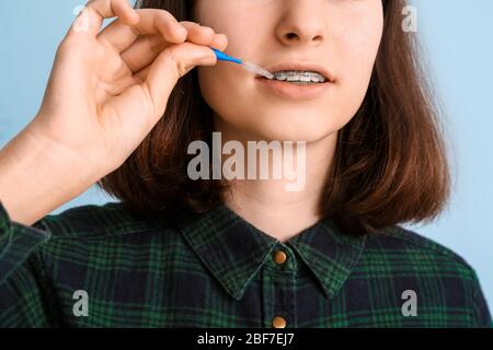 Ragazza adolescente con bretelle dentali e spazzola su sfondo chiaro, closeup Foto Stock