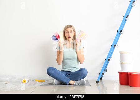 Donna scioccata che sceglie il colore della parete all'interno Foto Stock