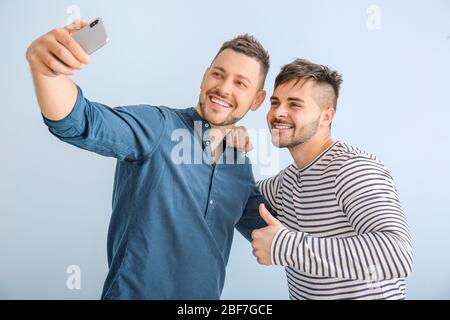 Ritratto di amici felici che prendono selfie su sfondo a colori Foto Stock