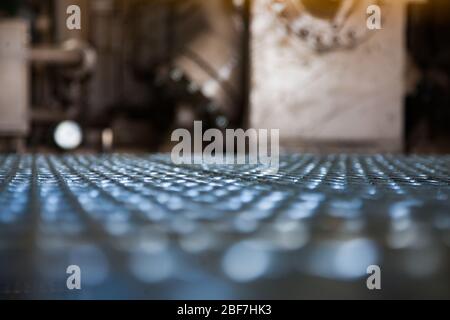 Contesto industriale astratto. Un pavimento a griglia nel magazzino della fabbrica. Breve profondità di campo. Foto Сlose-up. Foto Stock