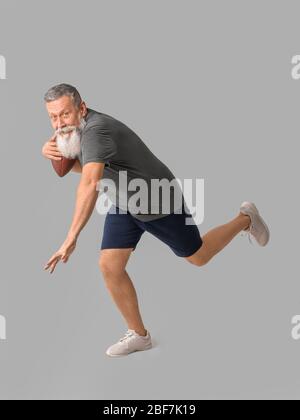 Uomo anziano sportivo con palla di rugby su sfondo grigio Foto Stock