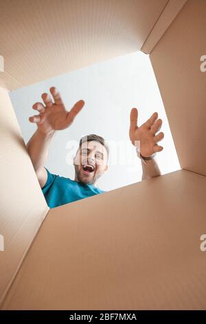 Uomo felice con scatola aperta, vista dall'interno Foto Stock