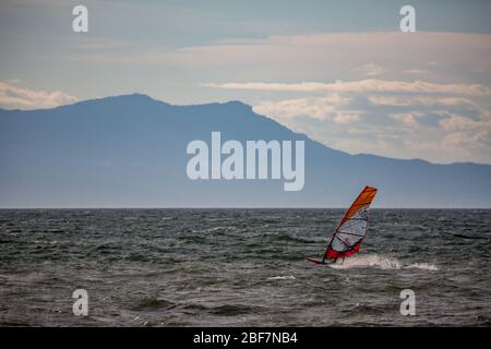 Ventoso pomeriggio inverno profilo windsurf nel mare di Tracia, paesaggio marino, sport acquatici divertimento, sport, attività, vacanza e concetto di viaggio. Grecia settentrionale vicino al villaggio di Porto Lagos Foto Stock