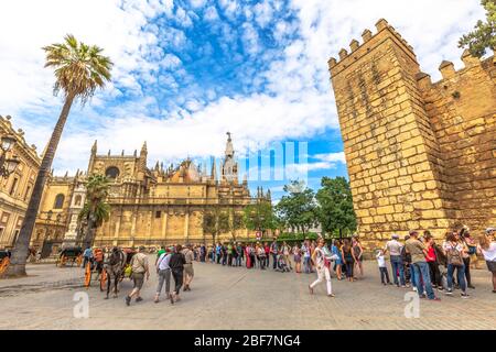 Siviglia, Andalusia, Spagna - 19 aprile 2016: Fila di turisti lungo le mura della fortezza moresca per visitare il reale Alcazar di Siviglia a Triumph Foto Stock