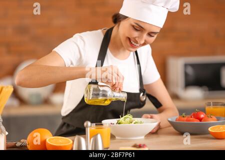 Chef femminile che prepara gustosa insalata in cucina Foto Stock