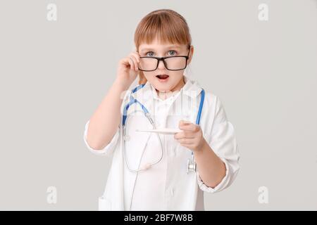 Sorpresi piccolo medico su sfondo grigio Foto Stock