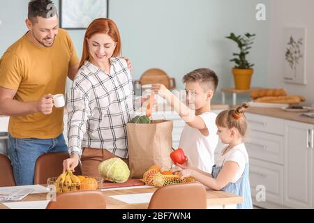 Famiglia disimballaggio prodotti freschi dal mercato in cucina Foto Stock