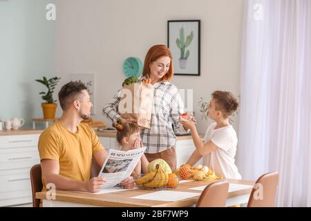 Famiglia disimballaggio prodotti freschi dal mercato in cucina Foto Stock