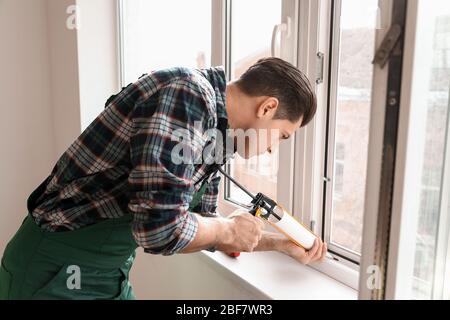 Lavoratore maschile installazione finestra in piano Foto Stock