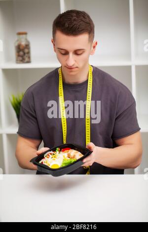Uomo che tiene una scatola piena di alimenti ricchi di proteine per la nutrizione sportiva Foto Stock