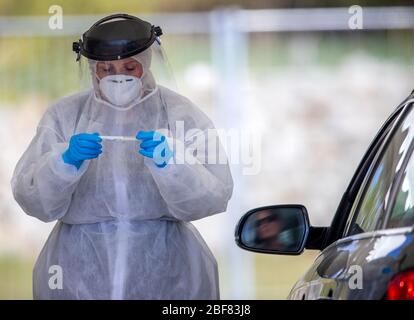 17 aprile 2020, Meclemburgo-Pomerania occidentale, Bützow: Utilizzando un tampone, Anja Hörichs preleva un campione da un paziente in auto presso il centro di test per la sospetta corona. Il campione viene prelevato dalla gola del paziente. Al centro di prova, presso il reparto di manutenzione stradale, vengono prelevati fino a 50 campioni al giorno. Foto: Jens Büttner/dpa-Zentralbild/dpa Foto Stock