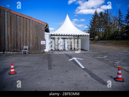 17 aprile 2020, Meclemburgo-Pomerania occidentale, Bützow: I dipendenti del centro di test per casi sospetti di corona attendono nei loro indumenti protettivi il paziente successivo. Il campione viene prelevato dalla gola del paziente. Fino a 50 campioni al giorno vengono prelevati presso il centro di test presso il reparto di manutenzione stradale. Foto: Jens Büttner/dpa-Zentralbild/dpa Foto Stock