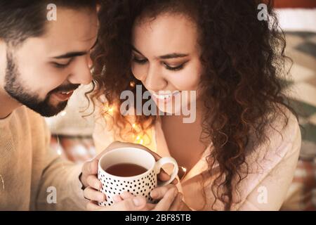 Buona coppia giovane con una tazza di tè in camera Foto Stock