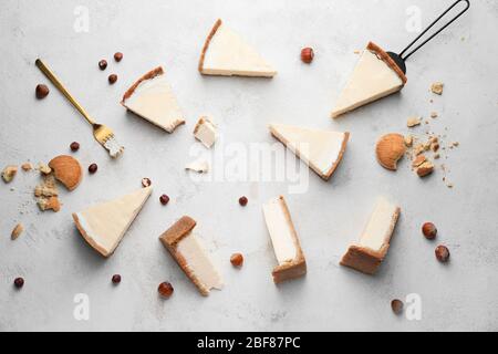 Composizione con pezzi di dolce e gustoso cheesecake su sfondo chiaro Foto Stock