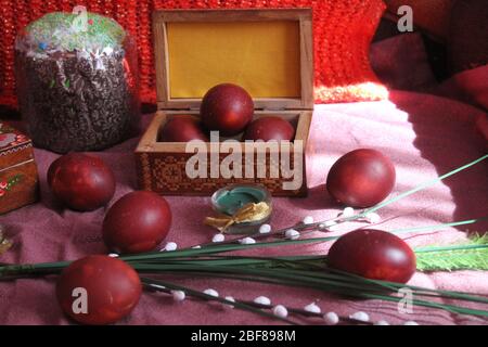 Uova dipinte di rosso con fiori e candele per la festa di Pasqua Foto Stock
