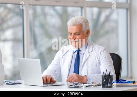 Medico di sesso maschile seduto a tavola in clinica Foto Stock