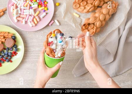 Donna che mangia dolci waffle a bolle d'aria al tavolo, vista dall'alto Foto Stock