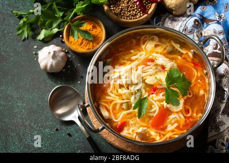 Zuppa di Tukpa cucina indiana. Zuppa di spaghetti caldi con zenzero di pollo, coriandolo e aglio in una ciotola su un tavolo scuro. Spazio di copia. Foto Stock