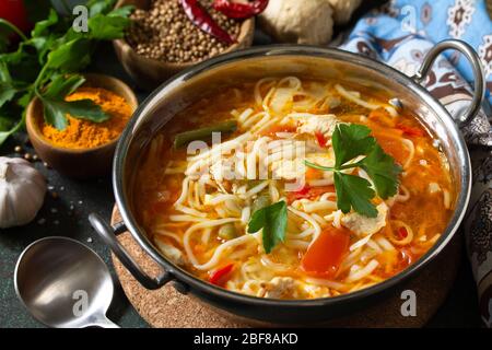 Zuppa di Tukpa cucina indiana. Zuppa di spaghetti caldi con zenzero di pollo, coriandolo e aglio in una ciotola su un tavolo scuro. Foto Stock