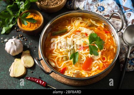 Zuppa di Tukpa cucina indiana. Zuppa di spaghetti caldi con zenzero di pollo, coriandolo e aglio in una ciotola su un tavolo scuro. Foto Stock