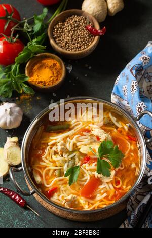 Zuppa di Tukpa cucina indiana. Zuppa di spaghetti caldi con zenzero di pollo, coriandolo e aglio in una ciotola su un tavolo scuro. Foto Stock