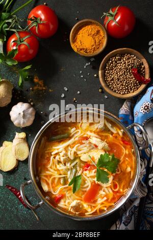 Zuppa di Tukpa cucina indiana. Zuppa di spaghetti caldi con zenzero di pollo, coriandolo e aglio in una ciotola su un tavolo scuro. Vista superiore sfondo piatto. Foto Stock