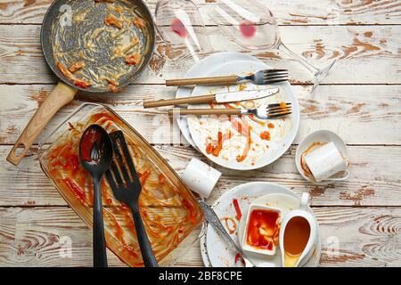 Piatti e stoviglie sporchi e vuoti su sfondo di legno Foto Stock