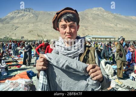 Ishkashim / Afghanistan - 5 ottobre 2013: Bel giovane afghano Pashtun sorride tenendo testa sciarpa nel mercato afghano tra Tagikistan e Afghanistan Foto Stock