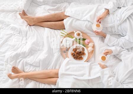 Giovane coppia che ha la colazione a letto a casa Foto Stock