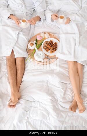 Giovane coppia che ha la colazione a letto a casa Foto Stock