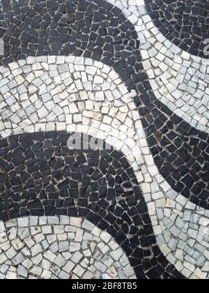 Marciapiede di Copacabana Beach, Brasile. Passeggiata di Rio de Janeiro. Sfondo, tessuto urbano. Vero disegno realizzato con piccole pietre nere e bianche. Foto Stock