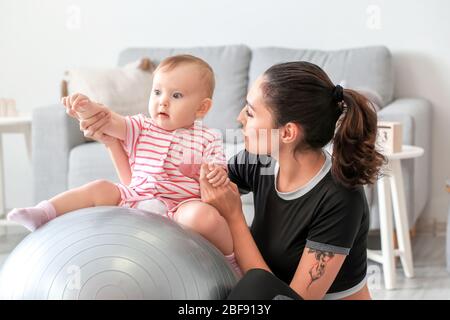 Giovane madre sportiva e il suo bambino che fa esercizi con il fitness a casa Foto Stock