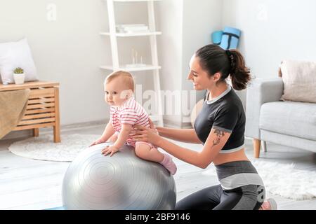 Giovane madre sportiva e il suo bambino che fa esercizi con il fitness a casa Foto Stock