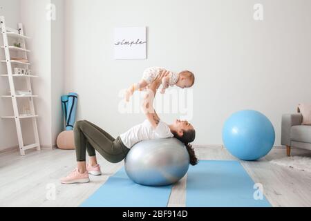 Giovane madre sportiva e il suo bambino che fa esercizi con il fitness a casa Foto Stock